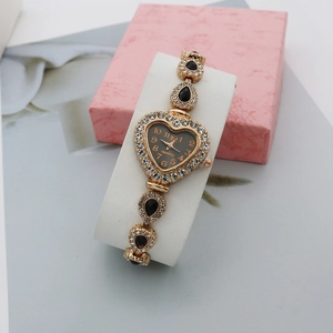 Vue détaillée d'une montre quartz dorée en forme de cœur avec gemmes noires sur son coussin