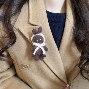 Detailed macro shot of a cute brown flocked rabbit brooch with lace scarf on a winter coat