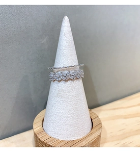 Detailed close-up of zircon petal rings on a white jewelry stand with wooden base