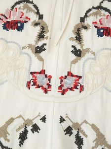 Détail macro de broderie florale au point de croix et paillettes sur tissu en coton beige