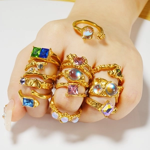 Close-up of golden stainless steel rings with colorful gemstones on a model's hand