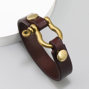 Close-up of vintage brass U-shaped buckle and brown leather strap on a punk style bracelet