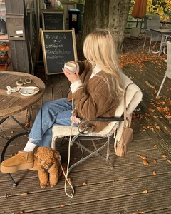 Gedetailleerd overzicht van de bruine gewatteerde jas in een herfstachtige straat