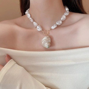 Detail of baroque pearl necklace with spiral shell pendant and golden toggle clasp