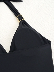 Dettaglio del costume da bagno nero con scollo all'americana e fibbia in metallo dorato