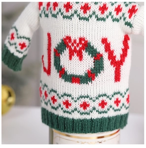 Detail of knitted Christmas wine bottle cover with JOY embroidery and festive texture