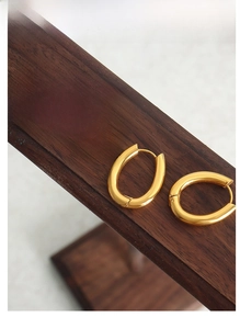 Polished 18K gold plated U-shaped geometric earrings on a premium wooden display