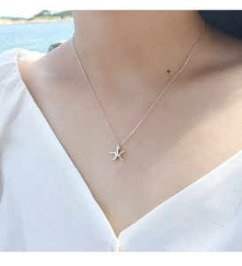 Close-up of S925 sterling silver starfish pendant necklace on a female model by the sea