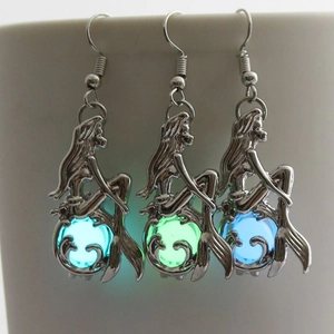 Luminous mermaid earrings showing cyan, green, and blue glow effects in the dark