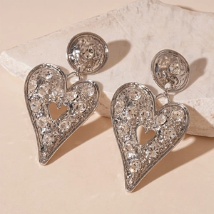Detailed view of silver heart earrings with rhinestone inlay and hammered metal texture