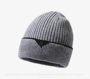 Detail view of grey ribbed knit beanie with black stripe and decorative shield logo patch