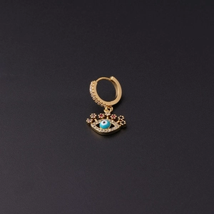 Macro shot of gold-plated evil eye earring with blue zircon stone on black background