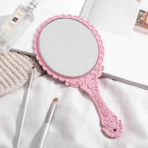 Pink vintage handheld makeup mirror with embossed floral pattern and bow design
