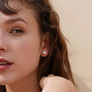 Close-up of cute cat-ear stud earrings with pearl inlay worn by a female model