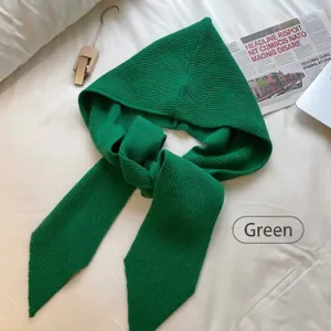 Detailed view of green knitted hooded scarf with ribbed texture on soft white fabric