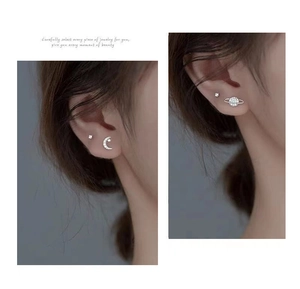 Close-up of asymmetrical 925 silver star and moon screw back stud earrings on ear