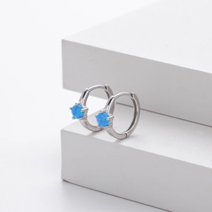 Macro detail of elegant silver hoop earrings featuring polished blue round opal stones