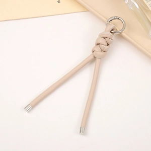 Detail of beige braided PU leather keychain with silver metal ring and knotted design