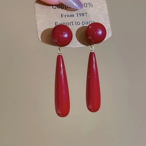 Close-up of deep red vintage teardrop earrings with high gloss finish on kraft card