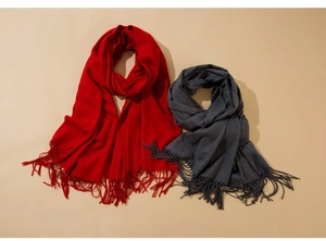Flat lay detail of solid red and dark grey scarves with elegant fringe tassels