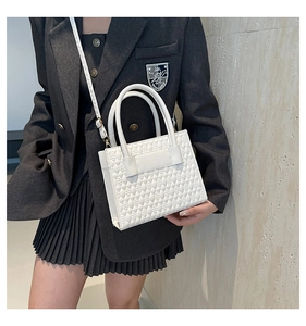 Sac à main matelassé blanc avec détails dorés porté avec une veste de blazer grise