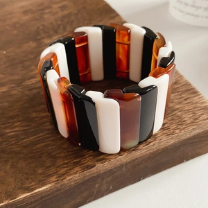 Macro detail of elastic resin bracelet with geometric amber and marble pattern tiles