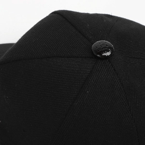 Macro detail of black twill baseball cap crown with faux crocodile skin texture button