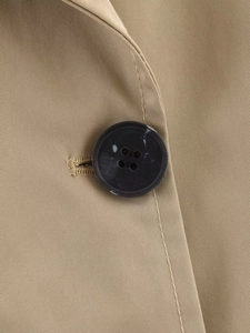 Macro detail of khaki twill fabric texture and black marble pattern button on the coat