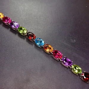 Dettaglio di pietre preziose ovali colorate incastonate in un bracciale d'argento