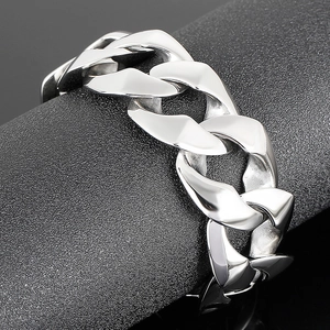 Polished silver stainless steel Cuban link bracelet for men on minimalist dark display stand