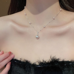 Close-up of elegant irregular pearl pendant necklace on model showing refined metal chain