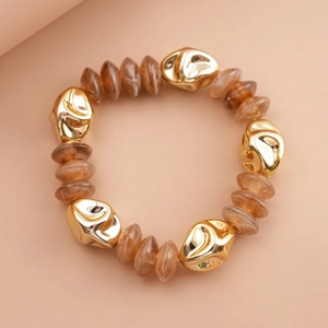 Detail of chunky gold geometric beads and translucent brown resin stones on a retro bracelet