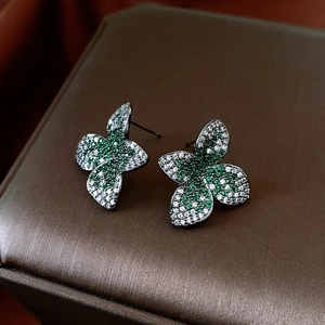 Macro shot of vintage flower stud earrings with white and green zircons on a jewelry box