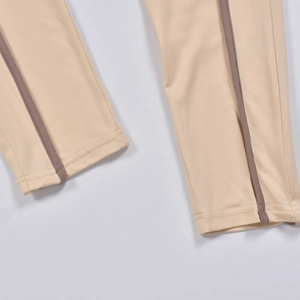 Détail de l'ourlet du body beige avec bandes latérales marron et texture de couture fine