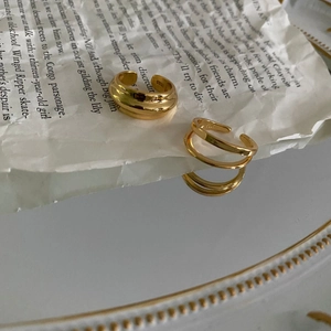 Artistic layout of two gold minimalist open rings on vintage parchment over a mirror