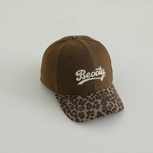 Detail of embroidered 'Beooty' text on brown cotton baseball cap with leopard print brim
