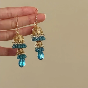 Detail of vintage gold hollow bell earrings with blue beads and tassel pendants
