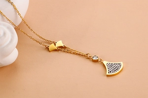 Close-up of golden necklace with fan-shaped pendant inlaid with clear crystal gems