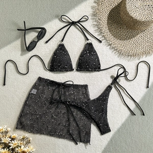 Detailed flat lay of three-piece black mesh bikini set with sequined texture and sarong
