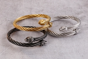 Gros plan de bracelets câbles à double tête de lion en finitions or, argent et noir