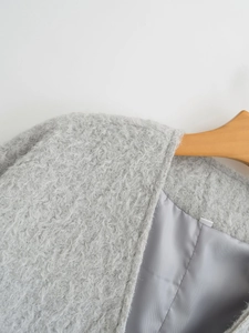 Detailansicht eines grauen Plüschmantels mit weichem Teddyfell und glattem Innenfutter