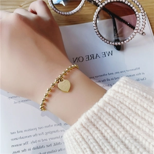 Elegant gold beaded bracelet featuring an engraved heart pendant for a minimalist look