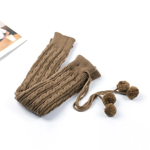 Detailed knit texture of thick coffee brown cable knit leg warmers with pom poms