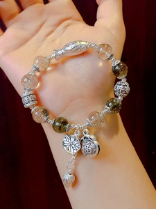 Detailed close-up of ethnic bracelet with green crystal beads and silver lotus charms