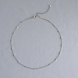 Detailed close-up of a silver minimalist necklace with small bar accents and lobster clasp