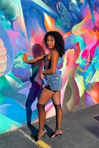 Dettaglio di collant neri velati con pantaloncini di jeans su un muro di graffiti