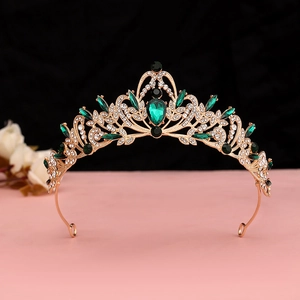 Close-up of golden Baroque crown featuring emerald green gems and white rhinestones