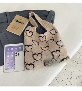 Détail du cabas en tricot à cœurs montrant l'espace de rangement avec iPad et iPhone