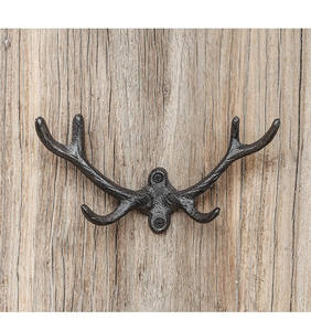 Detail of vintage cast iron antler wall hook with four prongs on rustic wood panel