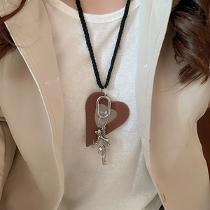 Detail of leather heart puppy pendant necklace on a model with neutral beige blazer